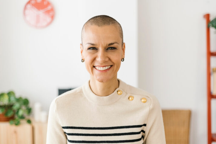 Woman with shaved head smiling into camera