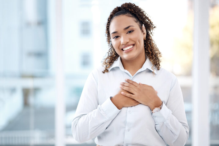 Smiling business woman with hands on chest
